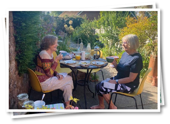 Two ladies enjoying afternoon tea in the garden at North View B&B, Penrith, surrounded by greenery and outdoor seating