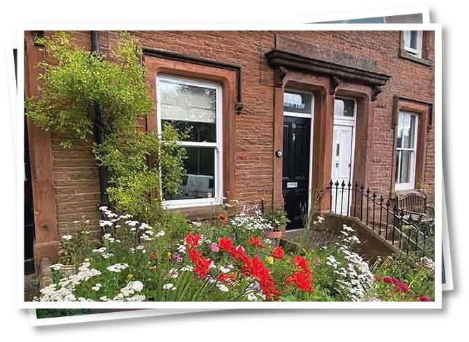 Front of North View B&B, a red brick Victorian terrace in Penrith with a colourful flower garden in front